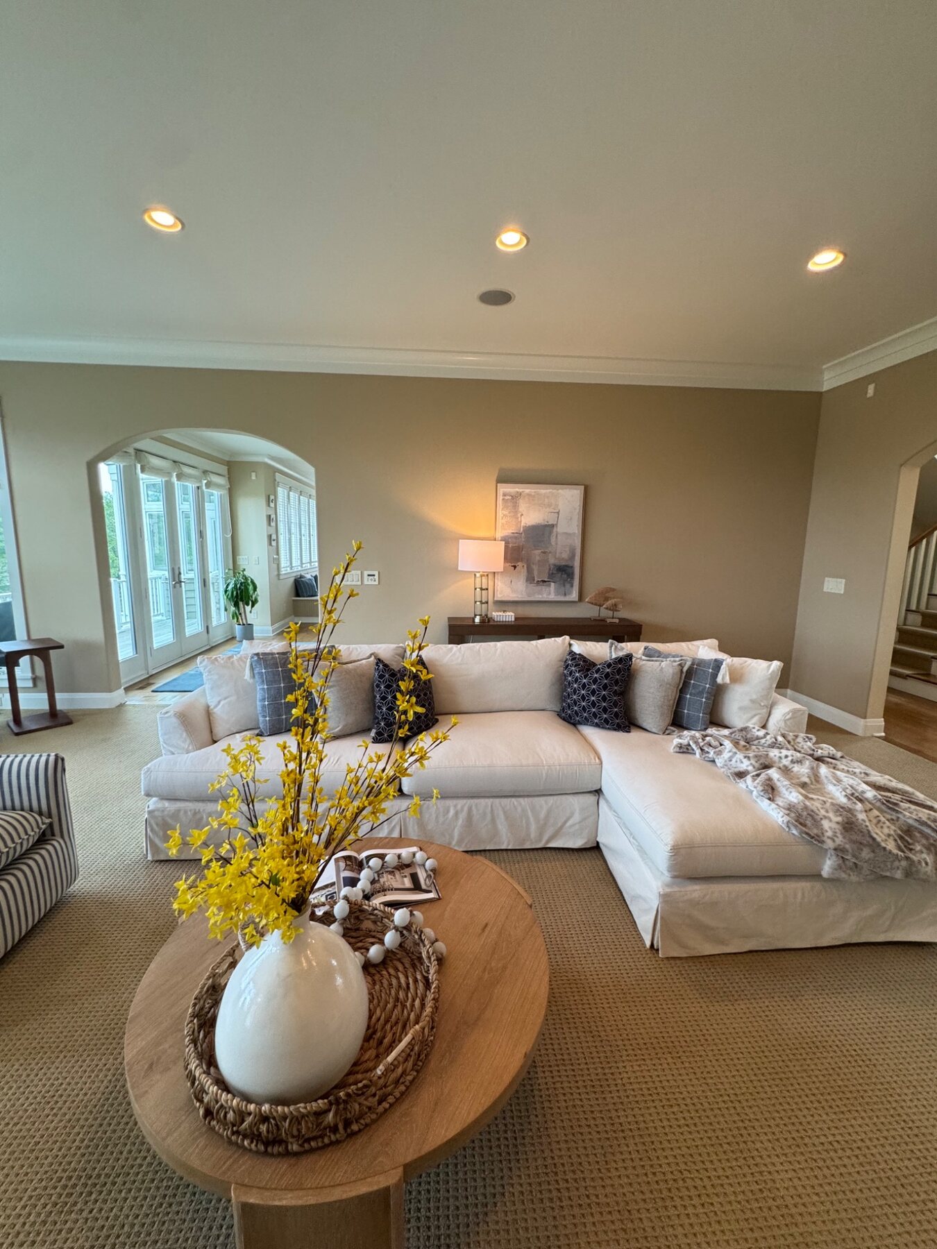 Lakehouse living room staged with a white sectional and sunny yellow branches